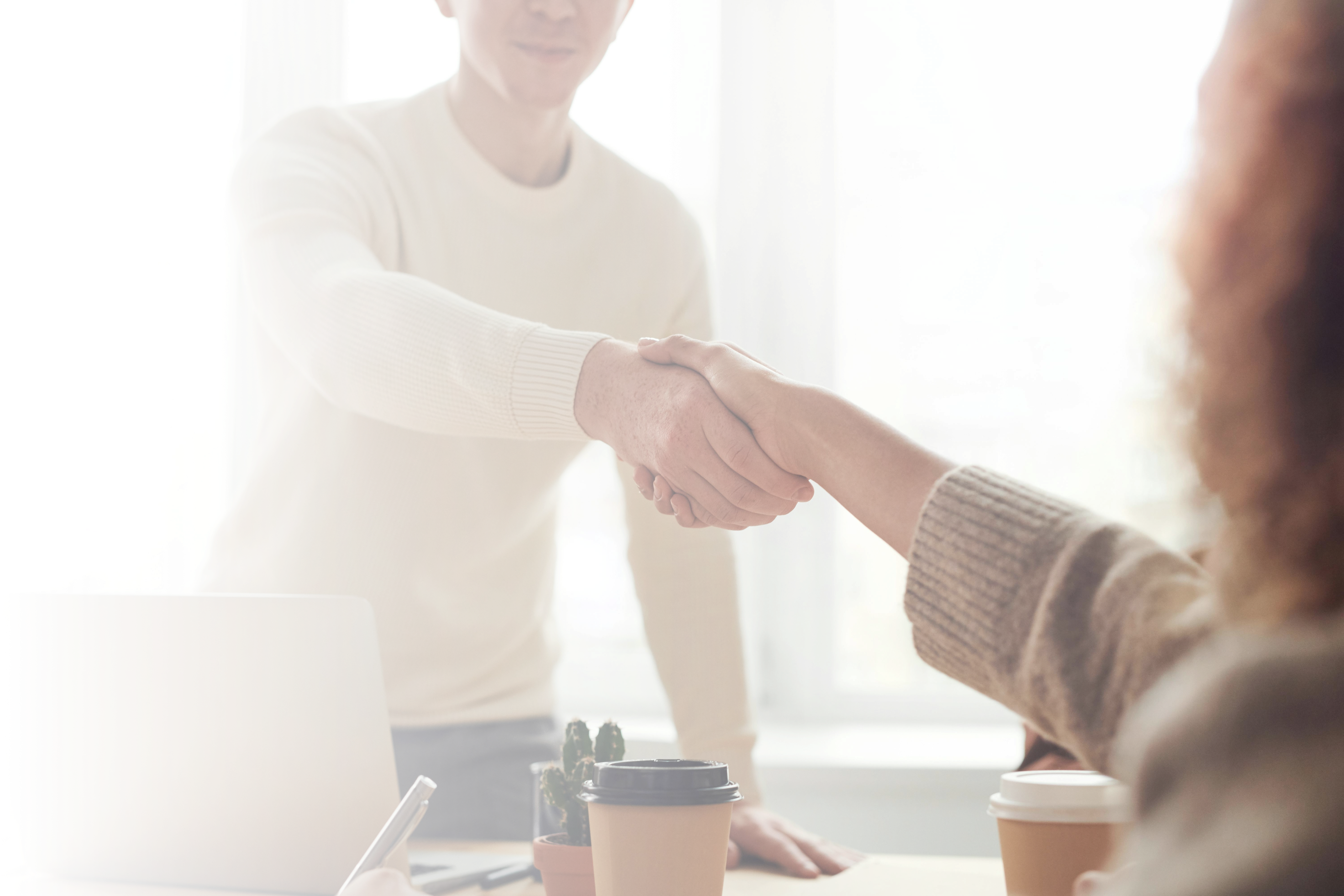 man and woman at a office table shaking hands